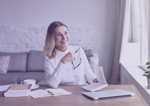 Smiling woman at home desk using CV examples to created her CV.